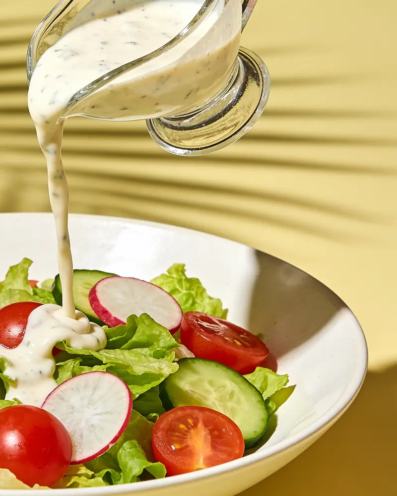 Ranch dressing poured over a garden salad